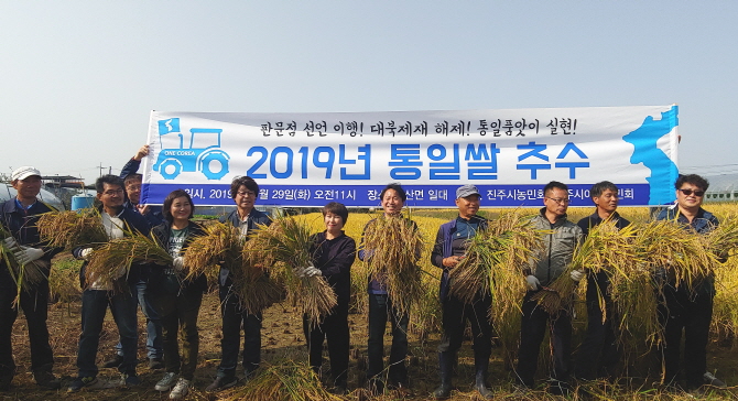 진주 통일쌀 추수 행사에 참가한 농민들이 수확한 나락을 들고 기념촬영을 하고 있다.