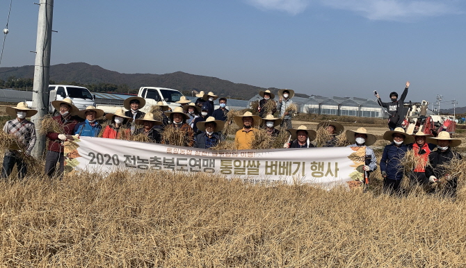 전농 충북도연맹 통일쌀 벼베기 행사 참가자들이 손에 낫과 벼를 들고 기념촬영을 하고 있다.