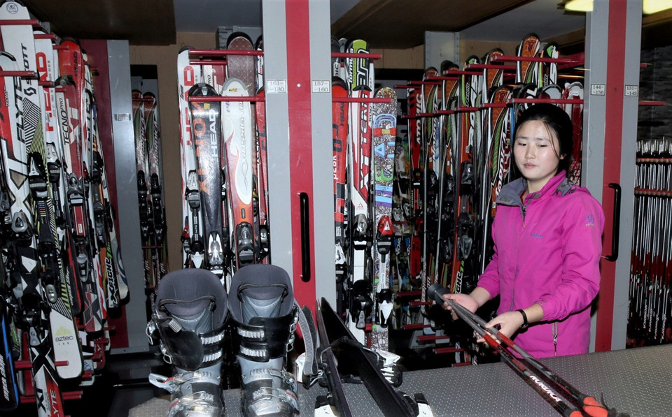 스키기재 대여점에서 여성 봉사원이 몸에 맞는 스키세트를 전해주고 있다. 2,000세트의 스키기재를 보유하고 있다.