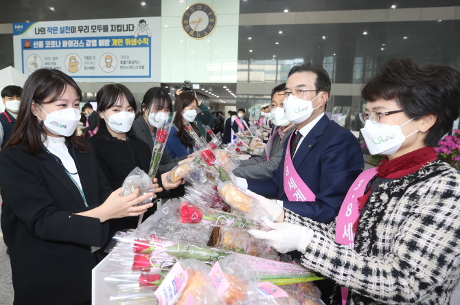 이성희 농협중앙회장(오른쪽 두번째)이 3월 8일 '세계 여성의 날'을 맞아 서울 중구 농협중앙회 본관에서 출근하는 직원들에게 장미꽃과 우리쌀 빵을 나줘주고 있다.