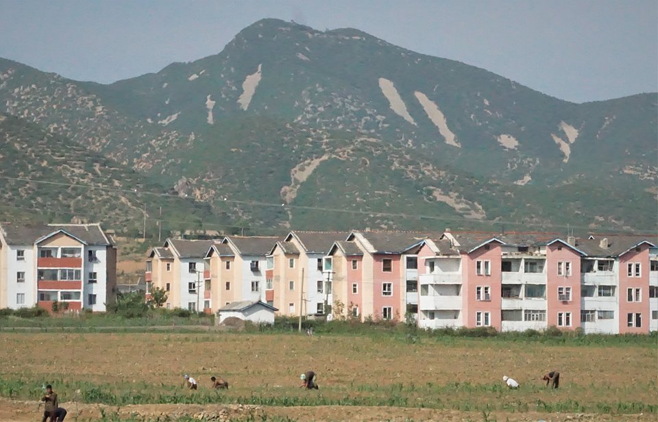 황해북도 봉산군 지역에서 주민들이 밭일을 하고 있다. 3층의 살림집이 보인다.