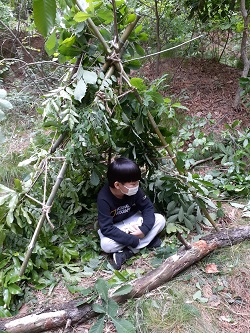 숲체험에 참가한 한 어린이 직접 나무를 베어 만든 아지트에서 쉬고 있다. 농체인 양업 제공