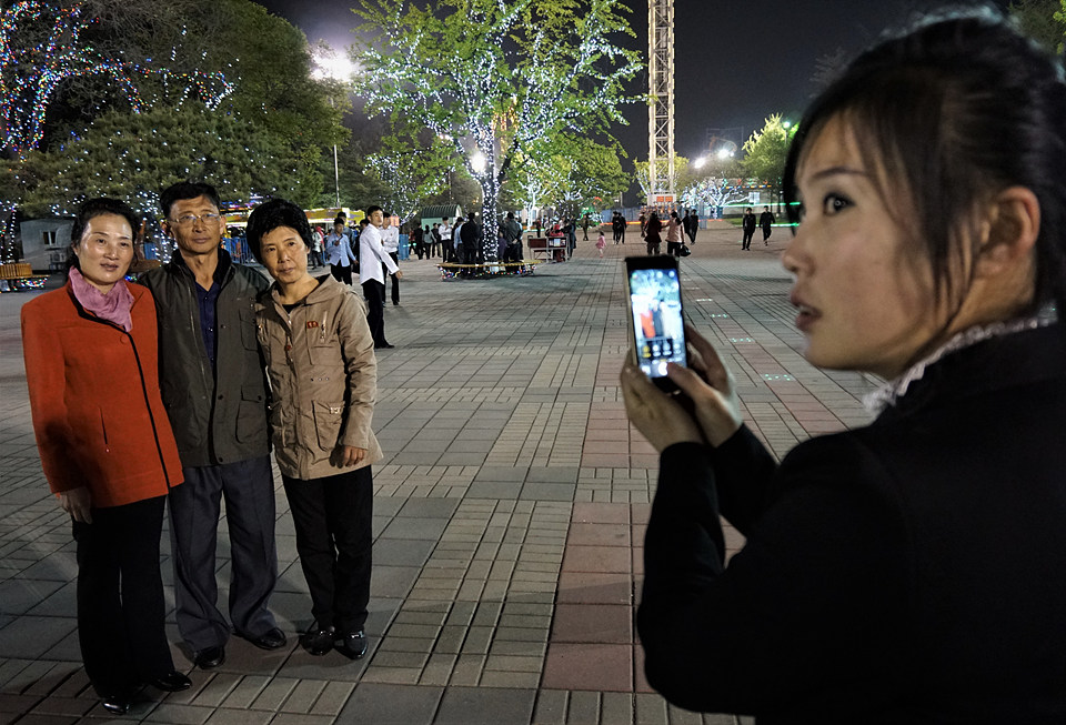 한 젊은 여성이 개선청년공원을 구경하면서 스마트폰으로 가족사진을 찍고 있다.