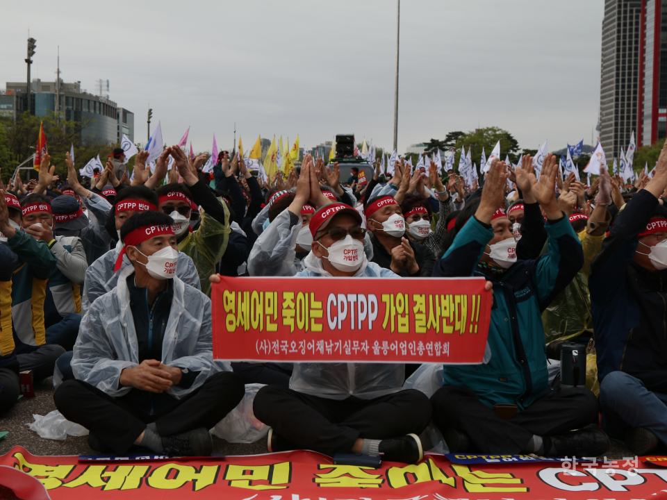 지난 13일 서울 여의도공원 광장에서 열린 ‘CPTPP 가입 저지 전국농어민대회’에 참여한 울릉도 오징어잡이 어민이 ‘영세어민 죽이는 CPTPP 가입 결사반대’라고 적힌 현수막을 펼쳐 보이고 있다.