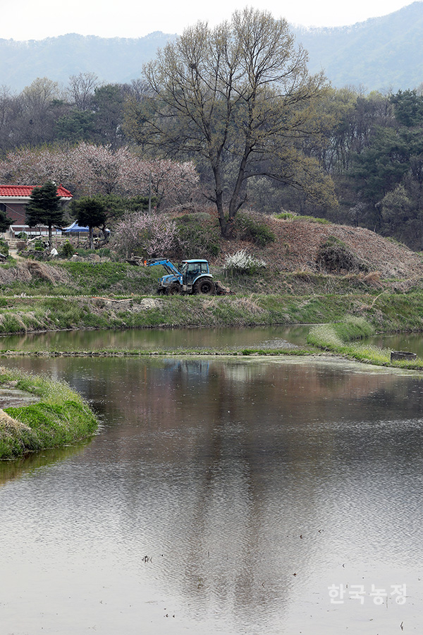 지난 18일 경기 여주시 북내면 상교리에서 한 농민이 트랙터로 써레질을 하는 모습이 물 댄 논에 반영돼 보이고 있다.