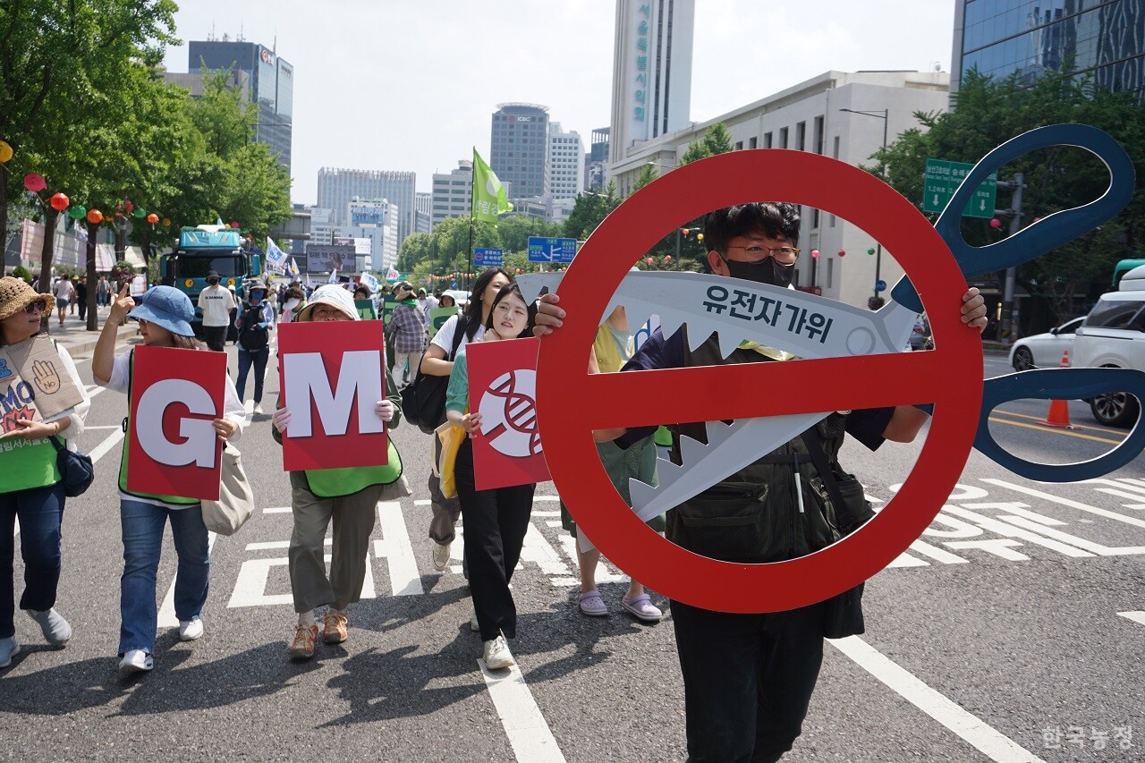 지난 20일 ‘2023 몬산토·바이엘 GMO반대시민행진’에 참가한 시민들이 서울 도심을 행진하고 있다. 참가자 중 한 명이 GMO법 개정을 통한 산업통상자원부의 유전자가위 기술 관련 규제완화(위해성 심사절차 완화) 시도를 반대하는 내용의 피켓을 들고 행진 중이다.