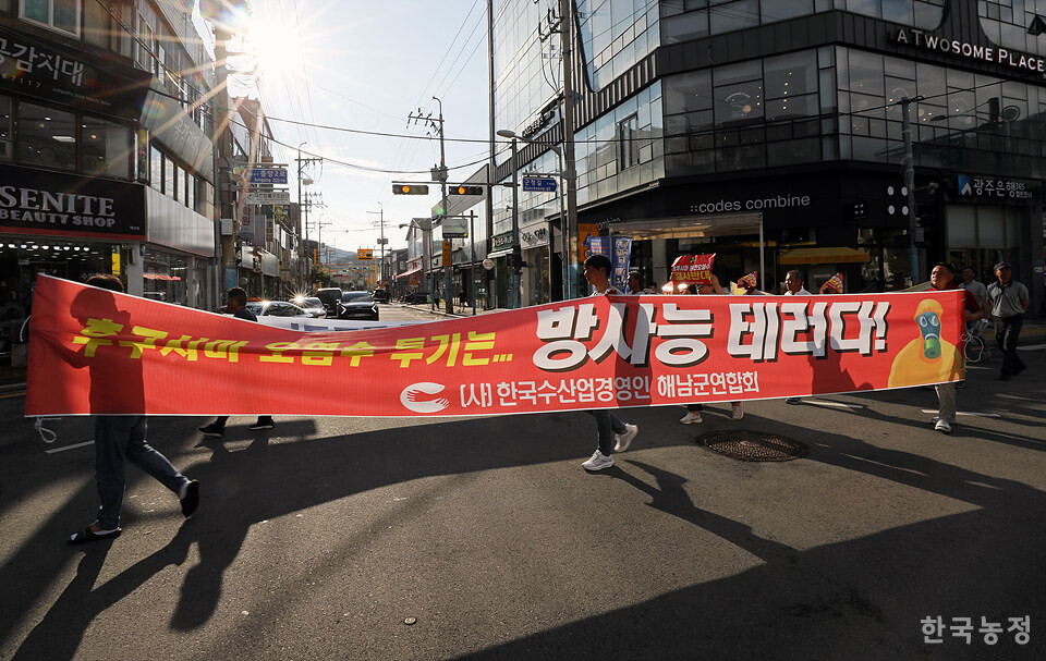 군민들이 ‘후쿠시마 오염수 투기는 방사능 테러다!’라고 적힌 현수막을 들고 행진하고 있다.