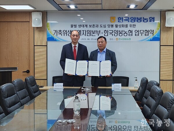 위성환 가축위생방역지원본부 본부장(왼쪽)과 김용래 한국양봉농협 조합장이 지난 25일 체결한 업무협약서를 내보이고 있다.