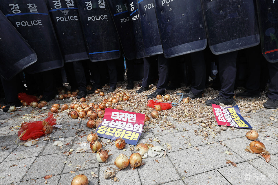 기획재정부 문 앞을 지킨 경찰들 발 밑에 농민들이 쏟아낸 수입 마늘과 양파 등이  뒹굴고 있다. 한승호 기자