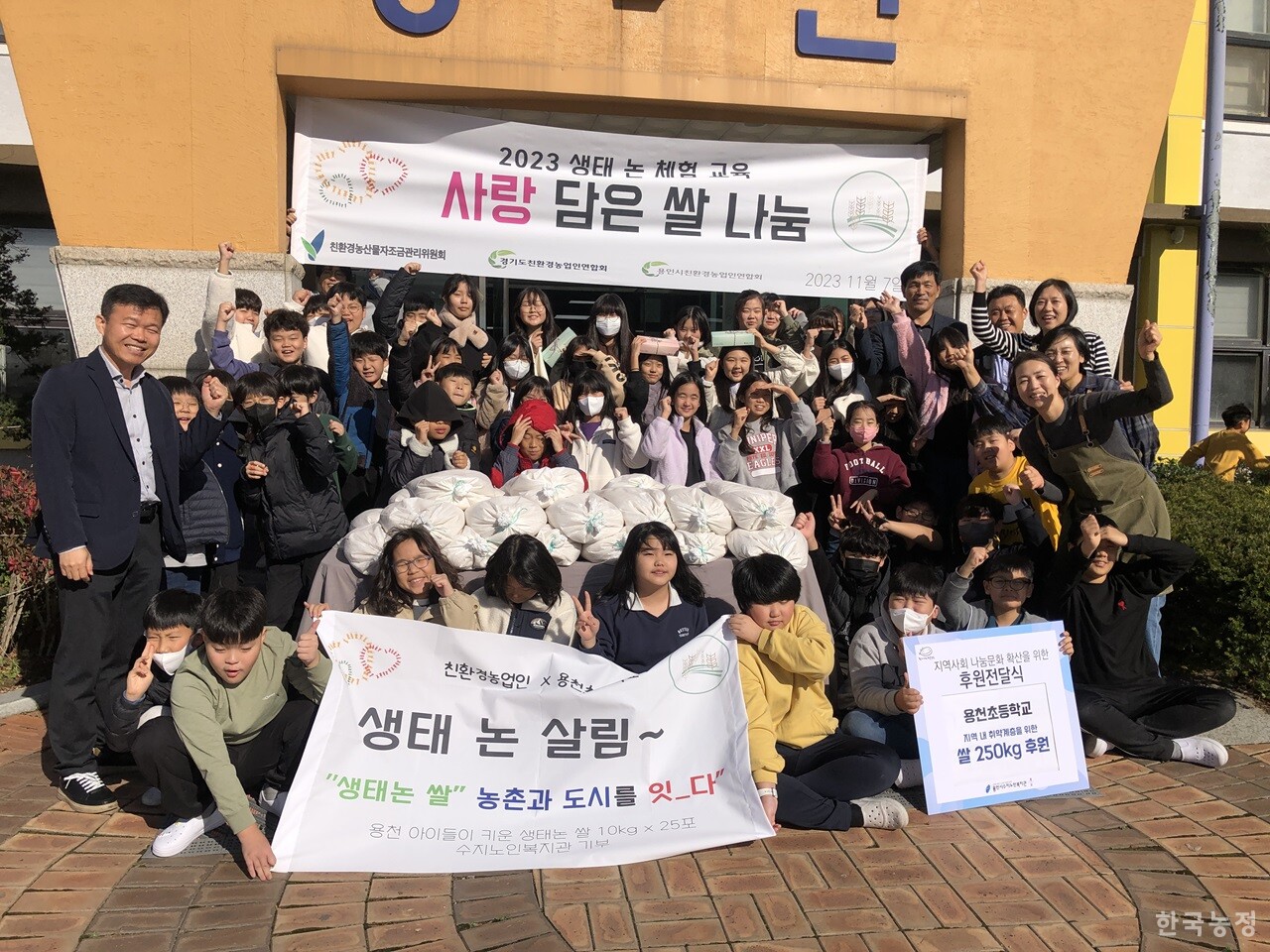 지난 7일 용인시 용천초등학교 본관 앞에서 열린 ‘2023 생태 논 체험 교육 - 사랑 담은 쌀 나눔’ 행사 직후 한자리에 모인 행사 참가자들.