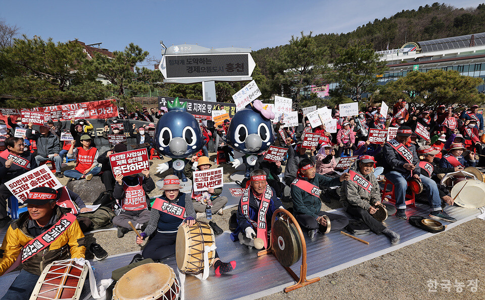 약 300여명의 홍천 지역 주민들이 곳곳에서 진행 중인 농촌파괴형 난개발 사업의 중단을 촉구하고 있는 가운데 전광판에 '군정비전'이 나타나고 있다.