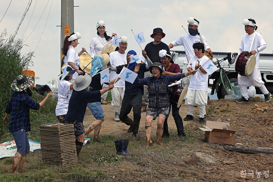 지난 1일 강원 철원군 철원읍 민간인통제구역 내에 마련된 철원군농민회 통일쌀경작지에서 열린 통일쌀 모내기에서 농민들과 인천도시농업네트워크 회원들이 풍물패와 어울리며 단일기를 흔들고 있다.