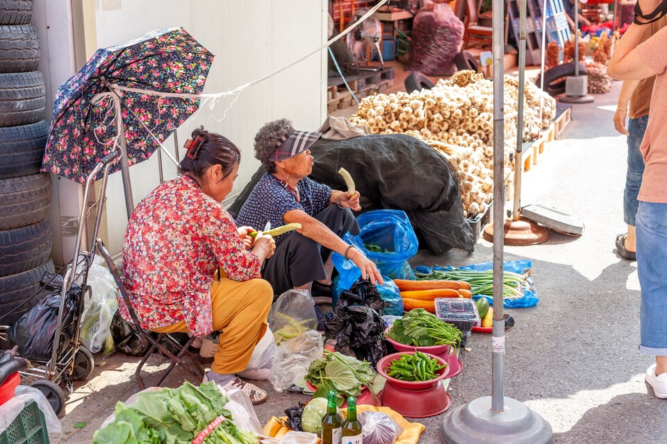 손님들에게 오이껍질을 벗겨 먹여보는 보령오일장의 상인. 더운 날에 수분도 보충할 겸 간식으로 먹기도 하는 오이다. 사진 류관희 작가