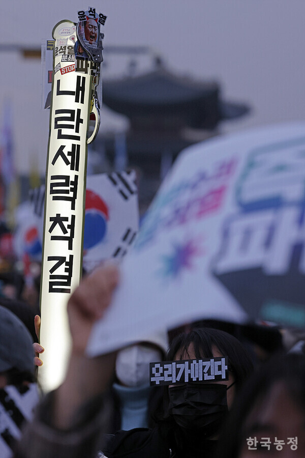 ‘우리가 이긴다’가 적힌 안경을 쓴 한 시민이 ‘내란세력척결’을 쓴 응원봉을 들고 윤석열 파면을 외치고 있다.