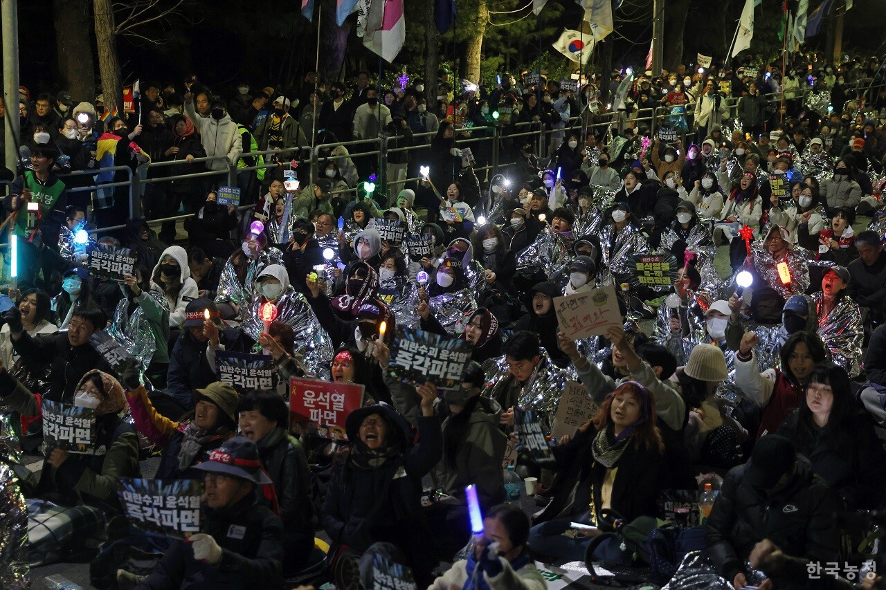지난 25일 농민들의 트랙터 행진을 막은 경찰에 항의하기 위해 남태령에 모인 시민들이 은박 담요로 몸을 감싼 채 밤늦게까지 “차 빼라”, “내란수괴 윤석열 즉각 파면하라” 등을 외치고 있다. 한승호 기자
