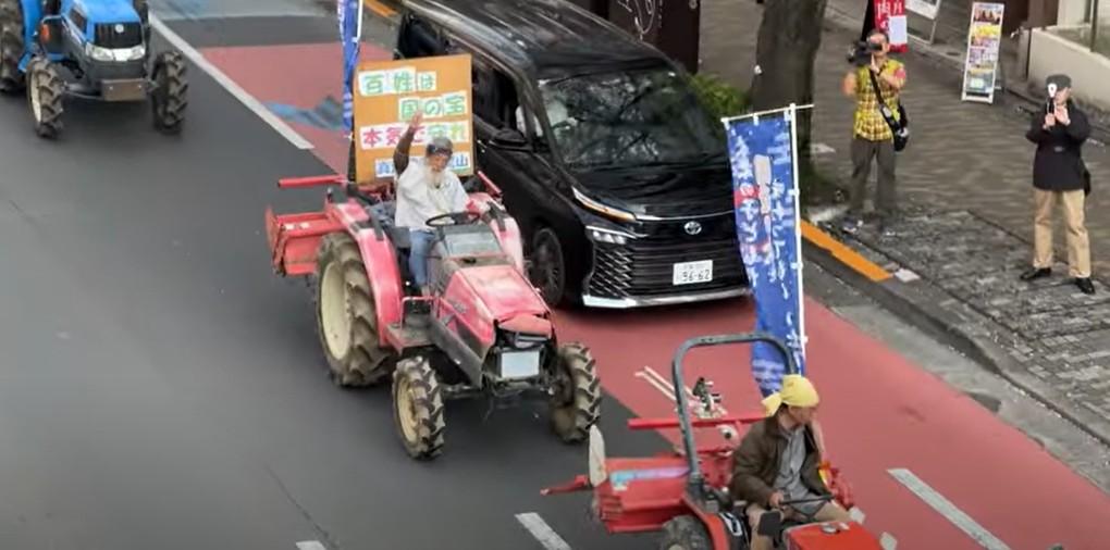 지난달 30일 일본 농민·시민들이 수도 도쿄를 비롯한 전국 각지에서 ‘레이와의 백성 잇키(농민봉기)’란 이름으로 트랙터 시위를 전개했다. 한 농민이 도쿄 도심의 도로에서 트랙터를 운전하며 시민들에게 주먹을 들어 보이고 있다. 유튜버 '에치젠야 히로유키 오전부' 영상 갈무리