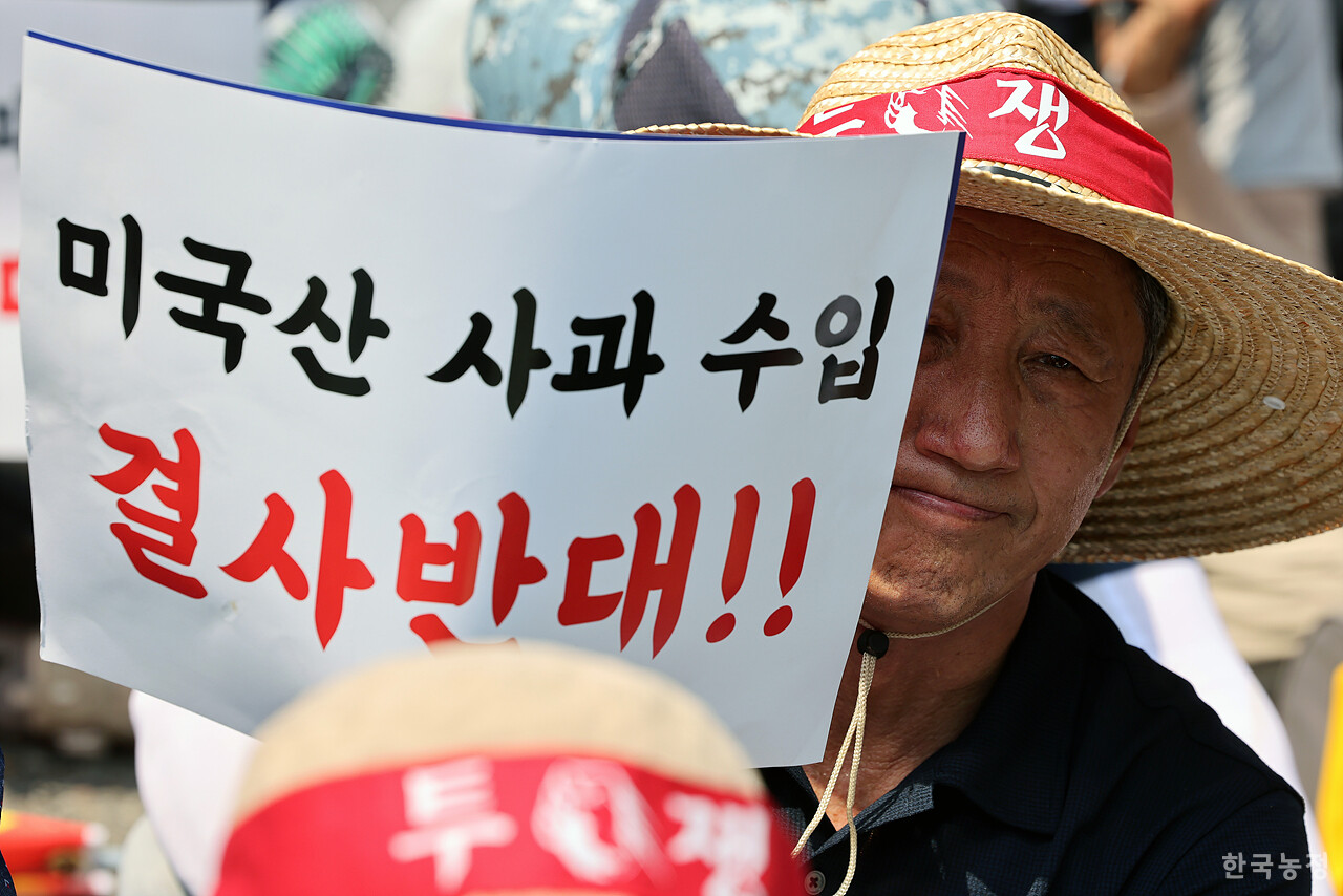 28일 오후 서울 용산 대통령실 앞에서 국민과함께하는농민의길·한국농축산연합회·한국종합농업단체협의회·축산관련단체협의회 공동 주최로 열린 ‘한-미 상호관세 협상 농축산물 개방 반대 전국농축산인 결의대회’에서 사과생산자협회 한 회원이 '미국산 사과 수입 결사반대'가 적힌 손팻말을 들고 굳은 표정을 짓고 있다. 한승호 기자