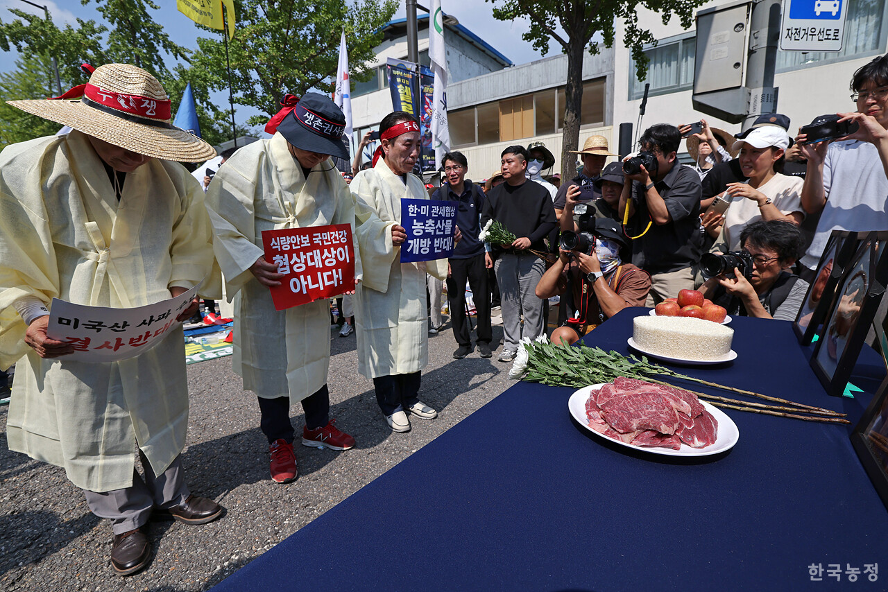 28일 오후 서울 용산 대통령실 앞에서 국민과함께하는농민의길·한국농축산연합회·한국종합농업단체협의회·축산관련단체협의회 공동 주최로 열린 ‘한-미 상호관세 협상 농축산물 개방 반대 전국농축산인 결의대회’에서 상복을 입은 농민단체 대표자들이 "관세 협상에서 더 이상의 양보와 추가 개방은 안 된다"며 쌀, 사과, 한우 등의 영정에 조화를 바치는 상징의식을 펼치고 있다. 한승호 기자