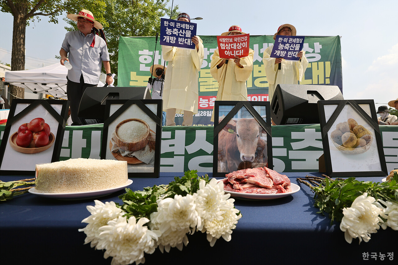 28일 오후 서울 용산 대통령실 앞에서 국민과함께하는농민의길·한국농축산연합회·한국종합농업단체협의회·축산관련단체협의회 공동 주최로 열린 ‘한-미 상호관세 협상 농축산물 개방 반대 전국농축산인 결의대회’에서 상복을 입은 농민단체 대표자들이 "관세 협상에서 더 이상의 양보와 추가 개방은 안 된다"며 쌀, 사과, 한우 등의 영정에 조화를 바치는 상징의식을 펼친 뒤 성명을 발표하고 있다. 한승호 기자