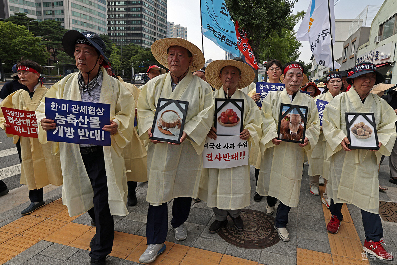28일 오후 서울 용산 대통령실 앞에서 국민과함께하는농민의길·한국농축산연합회·한국종합농업단체협의회·축산관련단체협의회 공동 주최로 열린 ‘한-미 상호관세 협상 농축산물 개방 반대 전국농축산인 결의대회’에서 상복을 입은 농민단체 대표자들이 "관세 협상에서 더 이상의 양보와 추가 개방은 안 된다"며 쌀, 사과, 한우 등의 영정사진을 들고 대통령실 방향으로 행진하고 있다. 한승호 기자