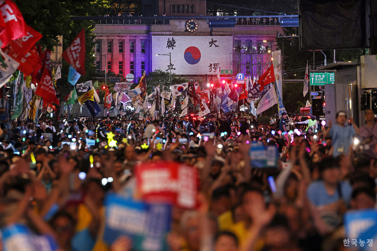 광복 80주년이었던 지난 15일 서울 숭례문 앞에서 열린 '광복 80년 평화 주권 역사정의 실현 8.15 범시민대회'에 참석한 농민, 노동자를 비롯한 수많은 시민들이 '평화 주권 역사정의 실현'을 외치고 있는 가운데 서울시청사에 내걸린 대형 태극기가 보이고 있다. 한승호 기자