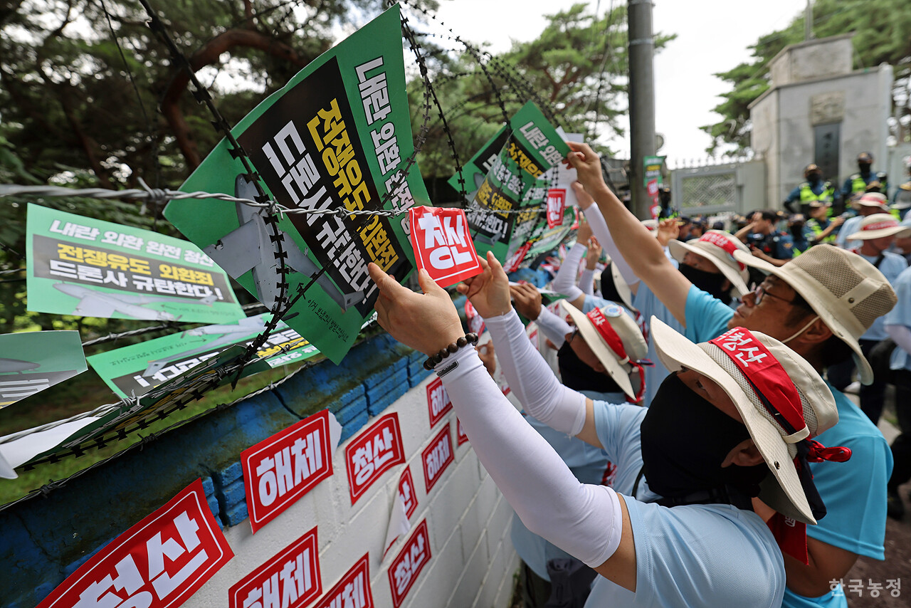 광복 80주년이었던 지난 15일 경기도 포천 드론작전사령부 앞에서 열린 '전쟁 유도 드론작전사령부 규탄대회'에서 2025 자주평화실천단에 참석한 농민, 노동자, 학생들이 '내란 외환 완전 청산'을 촉구하며 드론사 담벼락에 손팻말 및 '해체', '청산' 스티커를 붙이고 있다. 한승호 기자