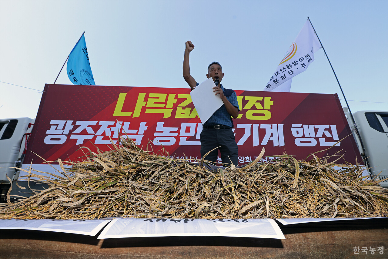 전국농민회총연맹 광주전남연맹과 전국쌀생산자협회 전남본부 회원들이 10일 오전 전남 무안군 농협중앙회 전남지역본부 앞 대로에서 ‘나락값 8만원 쟁취 농기계 행진’ 집회를 개최한 가운데 윤일권 전농 광전연맹 의장이 벼 깨씨무늬병이 걸린 나락을 앞에 놓고 대회사를 하고 있다. 한승호 기자