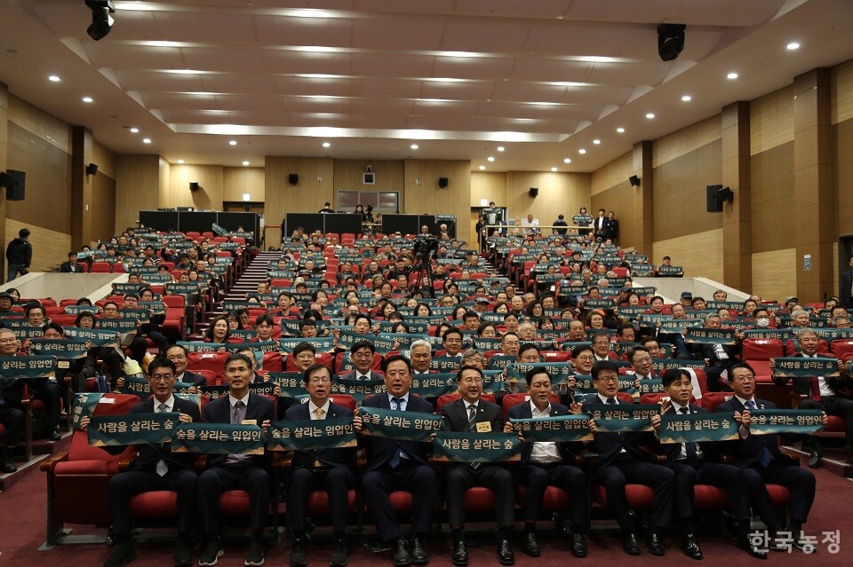 지난 4일 ‘제6회 임업인의 날’ 기념행사에 모인 임업인과 내빈들이 ‘사람을 살리는 숲, 숲을 살리는 임업인’이란 슬로건이 적힌 수건을 펼쳐들어 보이고 있다.