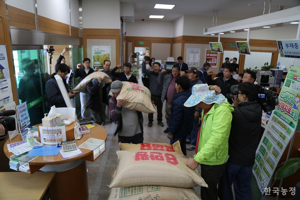 농협 안에 ‘8만원’ 글자가 적힌 나락 포대를 쌓는 농민들.