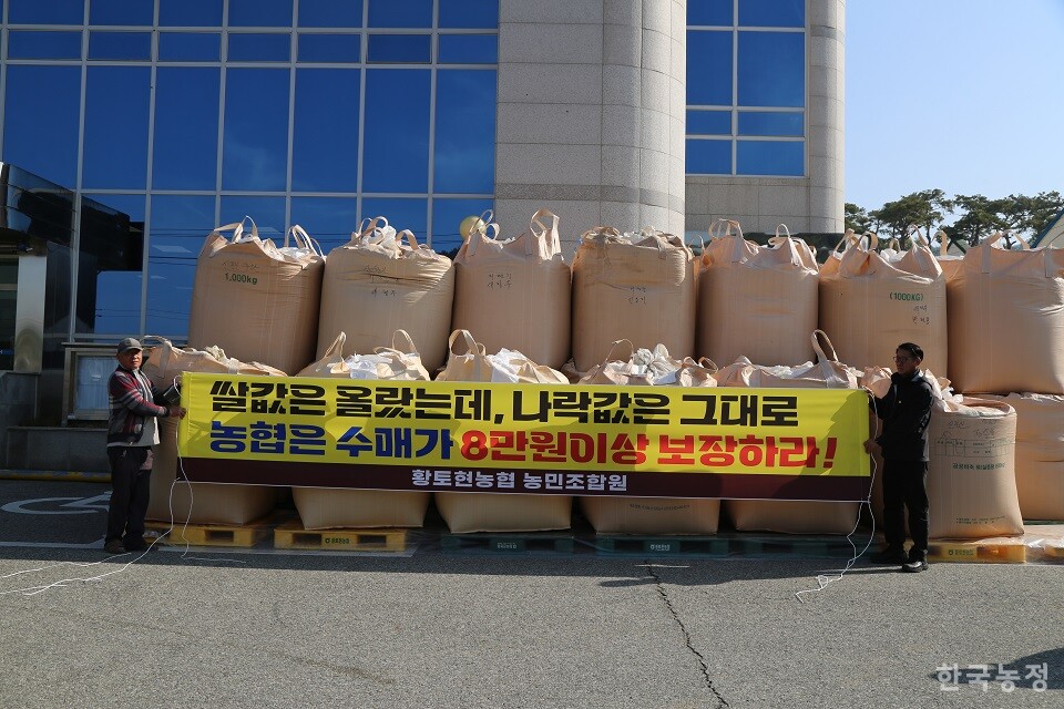 야적한 나락에 규탄 현수막을 붙일 준비를 하는 농민들.