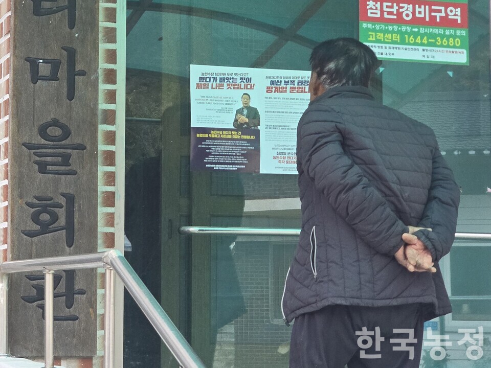 전북 순창군 쌍치면 마을회관에 농민수당 등을 삭감해 농어촌기본소득을 재원을 마련하겠다는 순창군의 발표를 규탄하는 벽보가 게시된 가운데, 한 농민이 이를 유심히 들여다보고 있다.