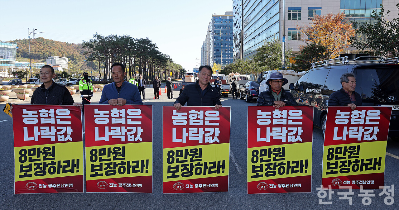 지난 14일 전남 무안군 농협중앙회 전남본부 앞에서 '나락값 8만원 보장 광주전남 농민대회'가 열린 가운데 농민들이 '농협은 나락값 8만원 보장하라'가 적힌 손팻말을 들고 서 있다. 한승호 기자