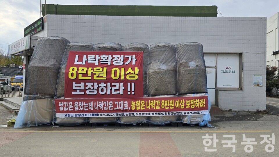 전북 고창 농민들이 지난 14일 8개 지역농협 앞에서 일제히 나락 적재 투쟁을 시작한 가운데, 고창농협 부안지점 앞에 ‘확정가 8만원 이상 보장’ 현수막이 걸린 나락이 쌓여 있다.