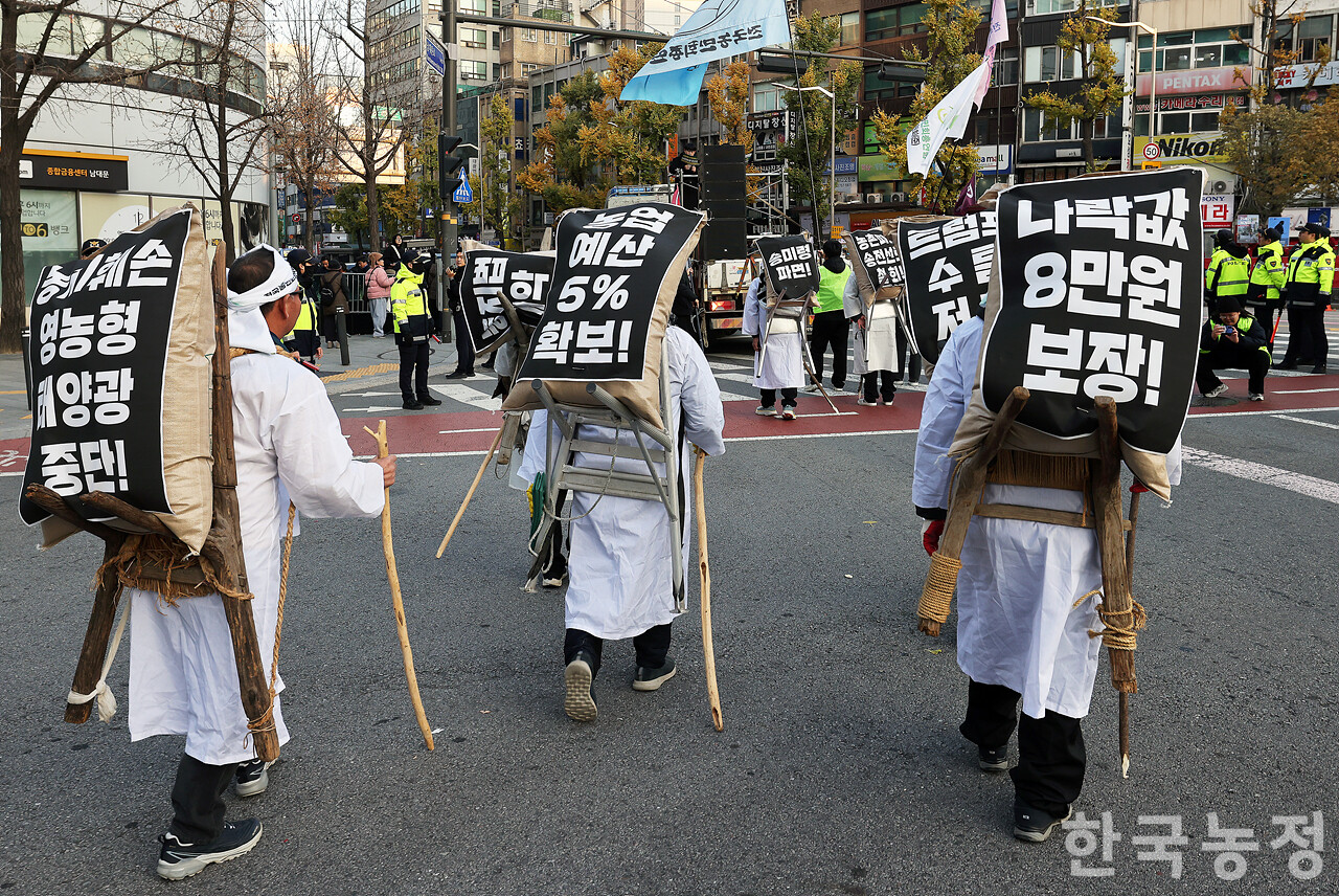 22일 오후 서울 숭례문 앞에서 열린 ‘기후재난 근본대책 수립! 농정대전환 실현! 2025 전국농민대회’에서 농민들이 '나락값 8만원 보장' 등 요구사항이 적힌 포대를 지게에 짊어지고 행진하고 있다. 한승호 기자