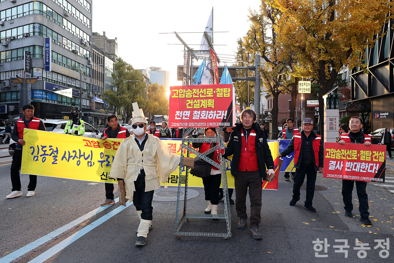 22일 오후 서울 숭례문 앞에서 열린 ‘기후재난 근본대책 수립! 농정대전환 실현! 2025 전국농민대회’에서 전남 영암지역 농민들이 고압송전선로·철탑 건설계획 전면 철회를 촉구하며 송전탑 모형을 앞세워 행진하고 있다. 한승호 기자