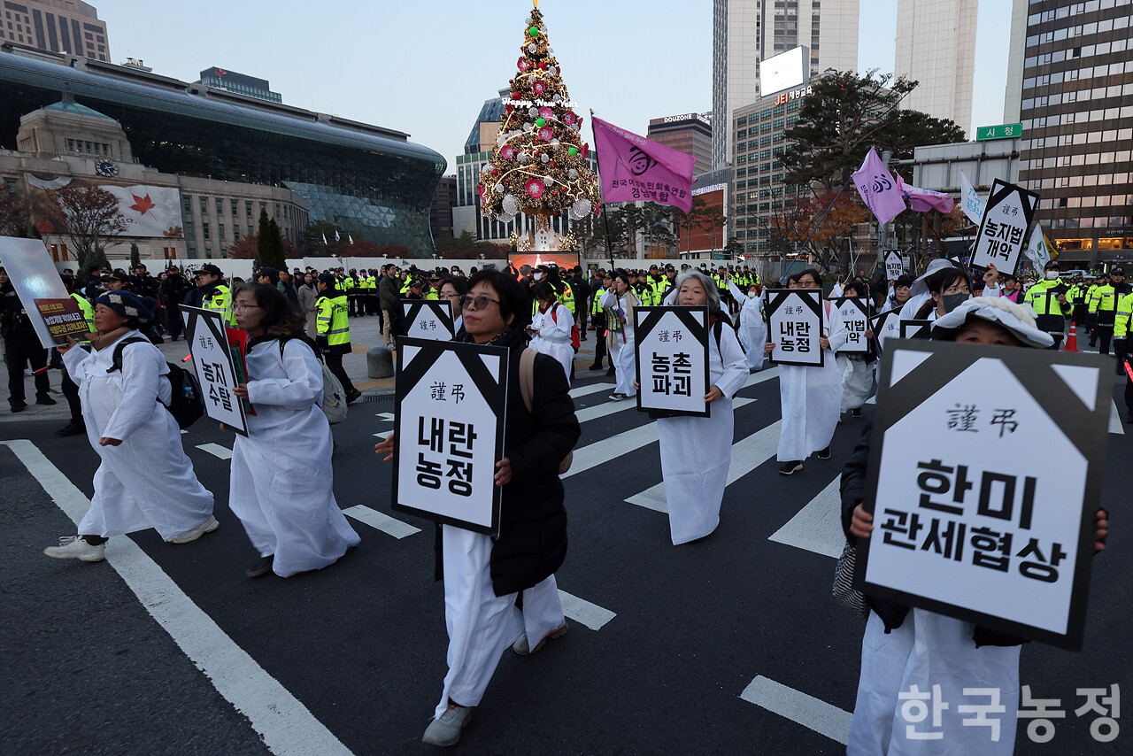 22일 오후 서울 숭례문 앞에서 열린 ‘기후재난 근본대책 수립! 농정대전환 실현! 2025 전국농민대회’에서 상복을 입은 여성농민들이 현 정부의 내란농정 등을 규탄하는 손팻말을 들고 행진하고 있다. 한승호 기자