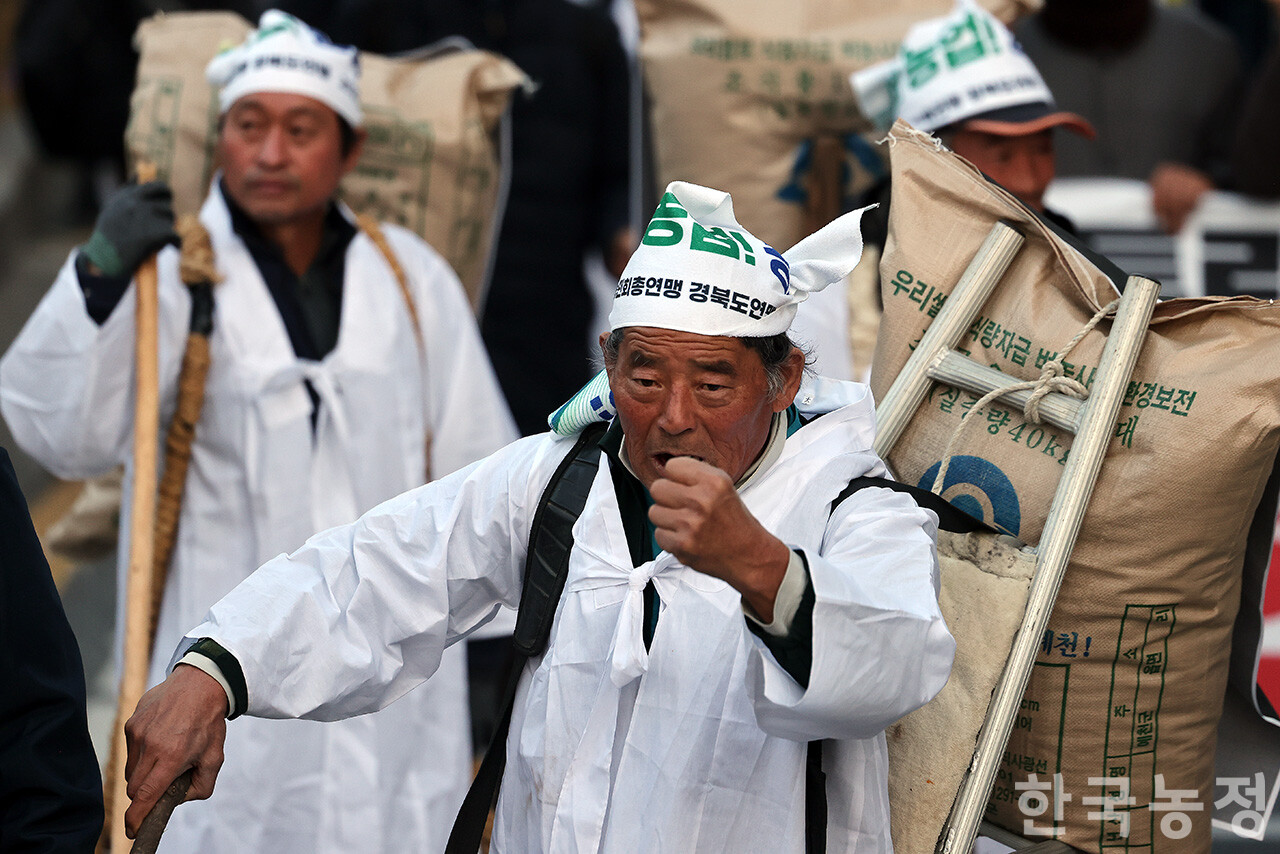 22일 오후 서울 숭례문 앞에서 열린 ‘기후재난 근본대책 수립! 농정대전환 실현! 2025 전국농민대회’에서 농민들이 '나락값 8만원 보장' 등 요구사항이 적힌 포대를 지게에 짊어지고 행진하고 있다. 한승호 기자