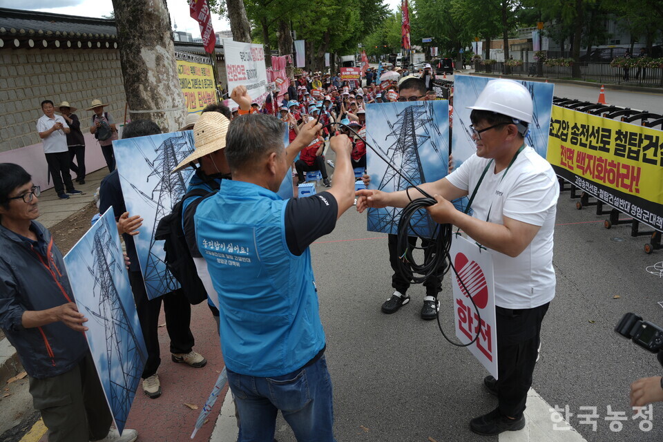 7일 청와대 사랑채 앞에서 열린 고압송전선로철탑건설반대영암군대책위원회 주관 송전선로 철회요구 영암군민 결의대회에서 주민들이 송전철탑의 위협속에서 선로를 끊어내는 내용의 상징의식을 진행하고 있다.