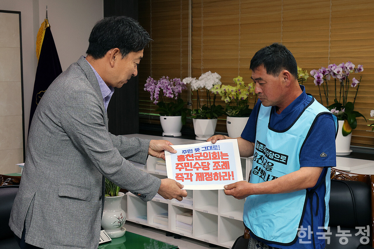 한현선 홍천군농민회장(오른쪽)이 정관교 군의회 의장에게 주민수당 조례 즉각 제정을 촉구하는 서한을 전달하고 있다. 한승호 기자