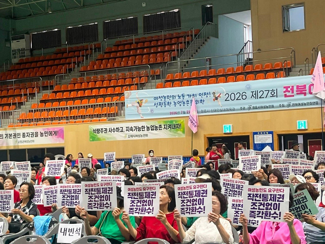 지난 21일 전북 정읍시 신태인체육관에서 열린 ‘2026 제27회 전북여성농민한마당’에 참가한 전여농 전북연합 회원들이 미군의 한국군을 향한 전시작전통제권 즉각 환수 촉구 피켓을 들고 있다. 전국여성농민회총연합 전북연합 제공